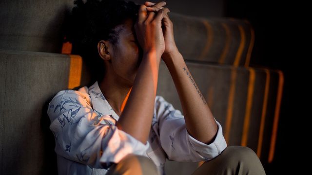 A woman sat on the floor with her head in her hands. 