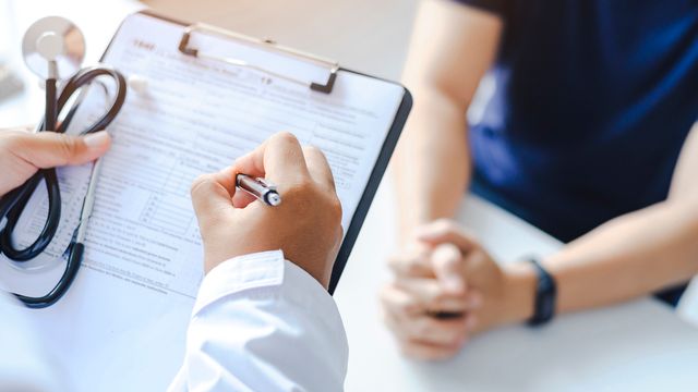 A doctor writing on a clipboard. 