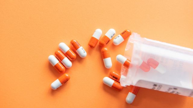 Orange and white pills spill from a prescription bottle. 