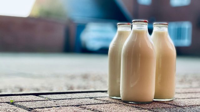 Three glass milk bottles on a doorstep. 