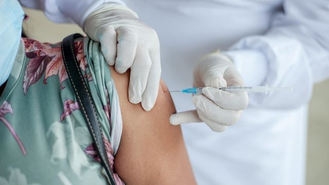 A medical professional administers a vaccination to a woman's upper arm. 