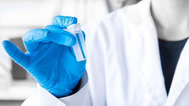 Lab worker holding a cuvette. 