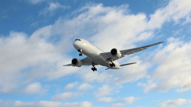 An airplane taking off into blue sky with clouds. 